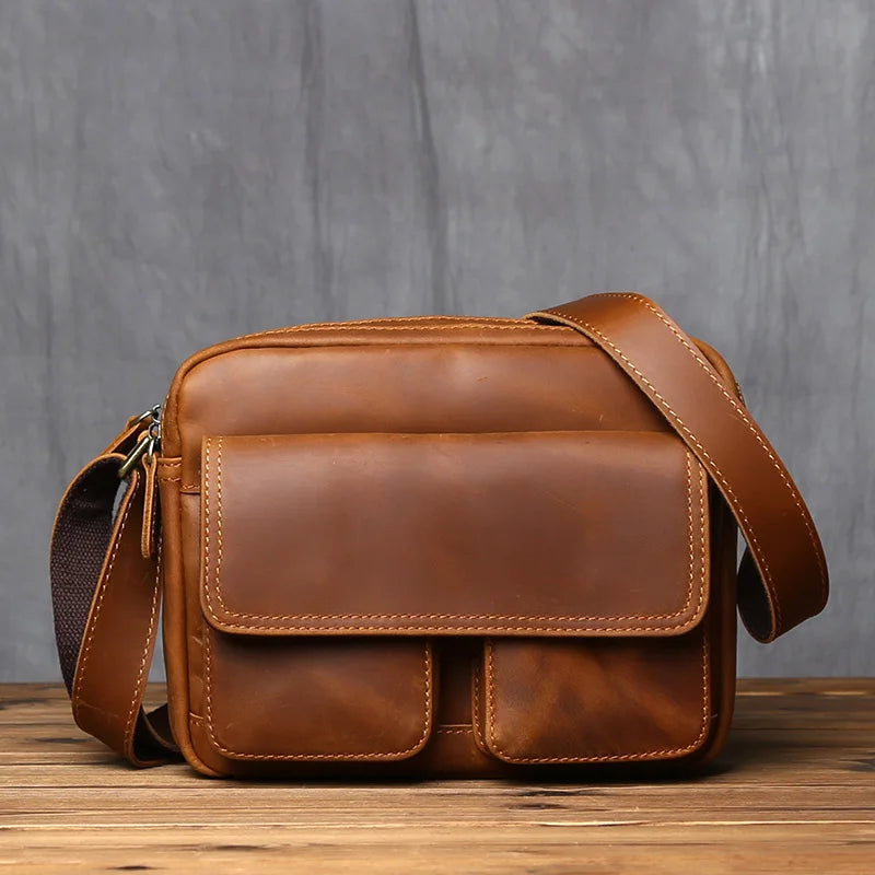 Brown leather satchel bag on a wooden surface with a gray background
