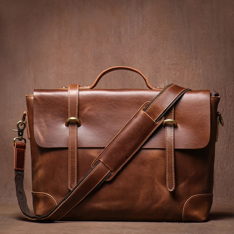 Brown leather satchel bag with a shoulder strap on a brown background