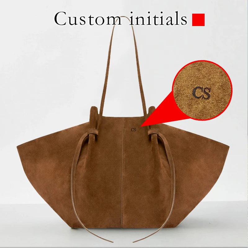 Brown suede handbag with 'CS' initials on a white background