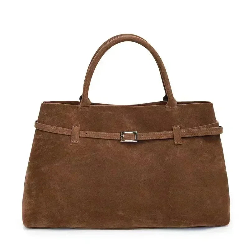Brown suede handbag with a belt detail on a white background