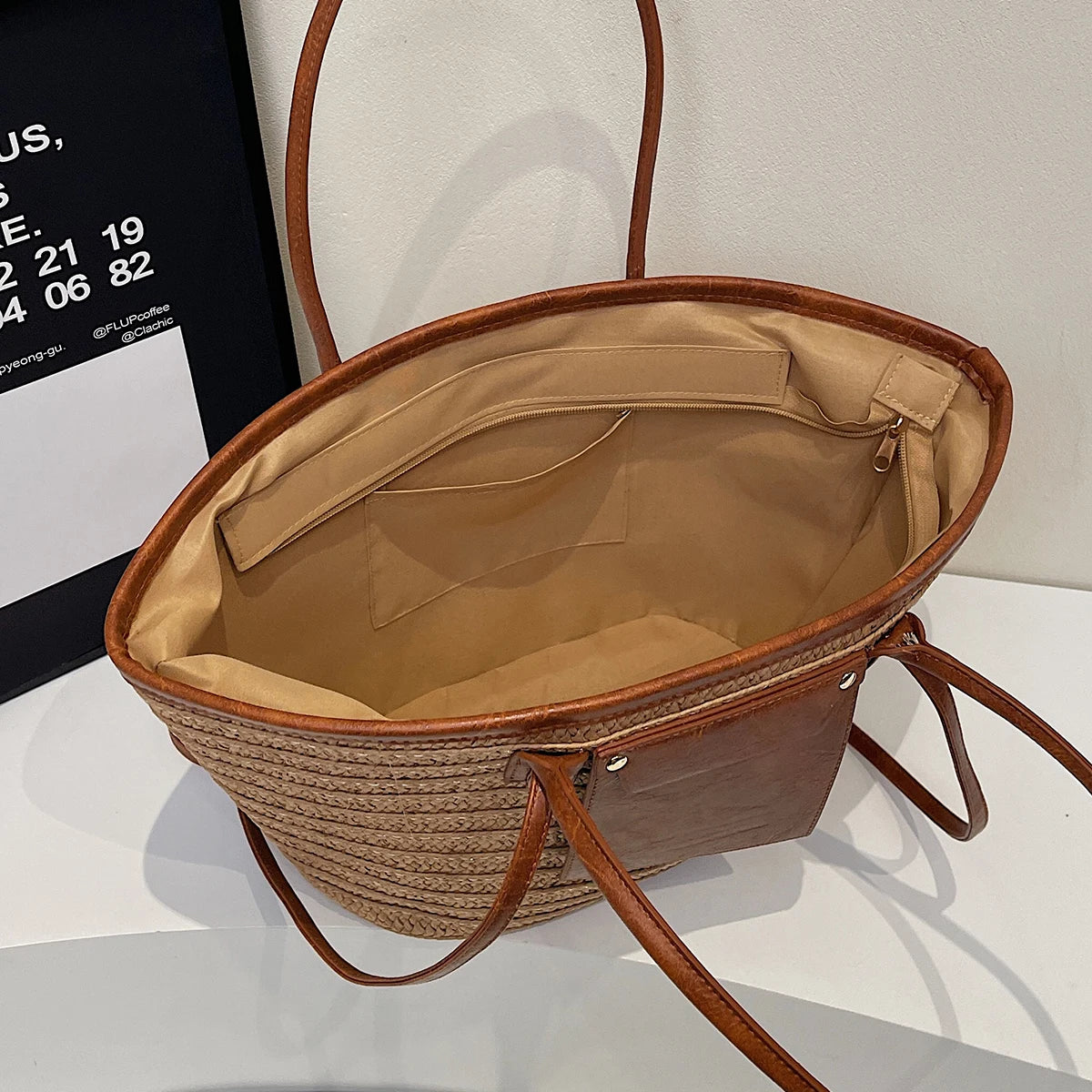 Brown woven handbag with beige interior on a white background