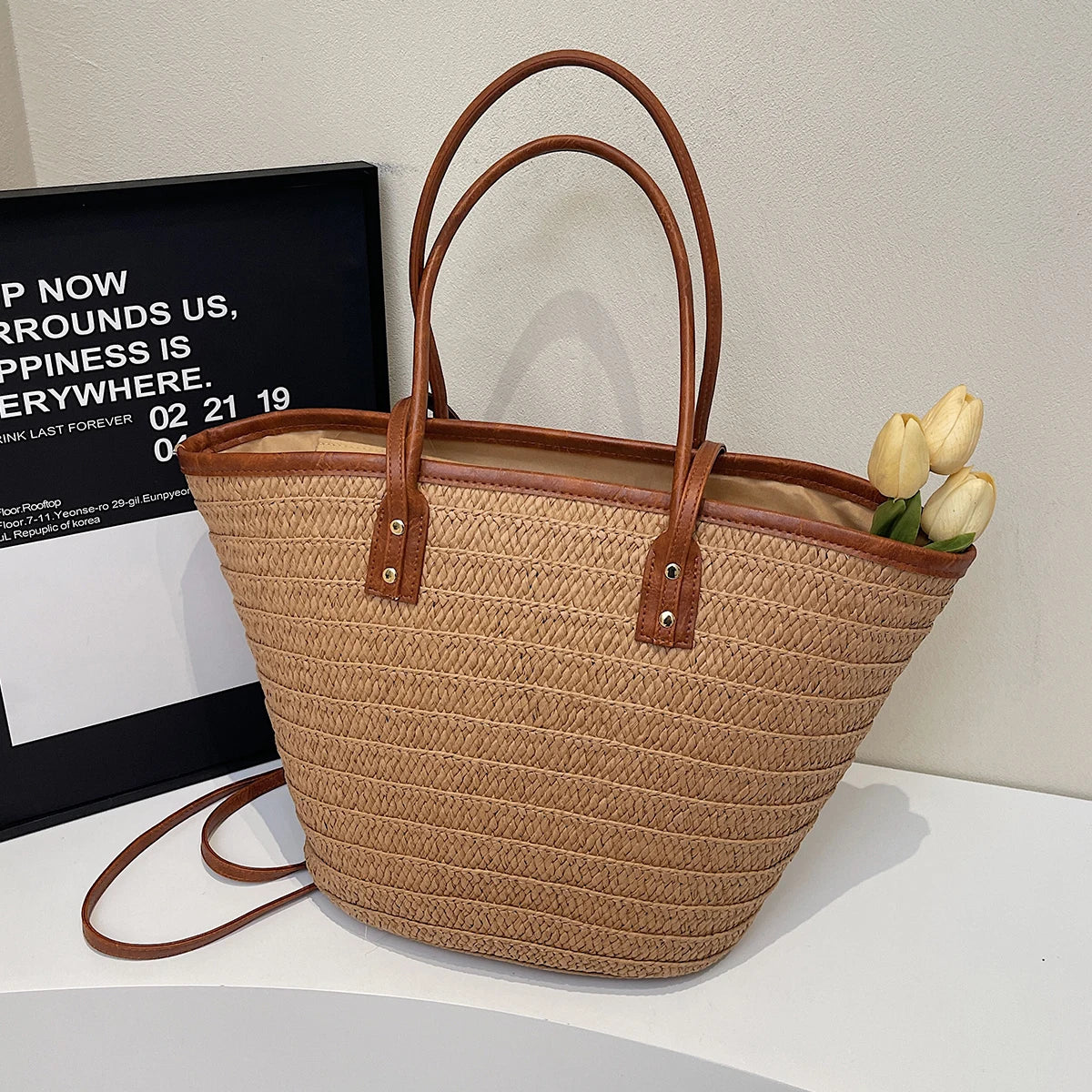 Brown woven tote bag with brown handles on a white surface