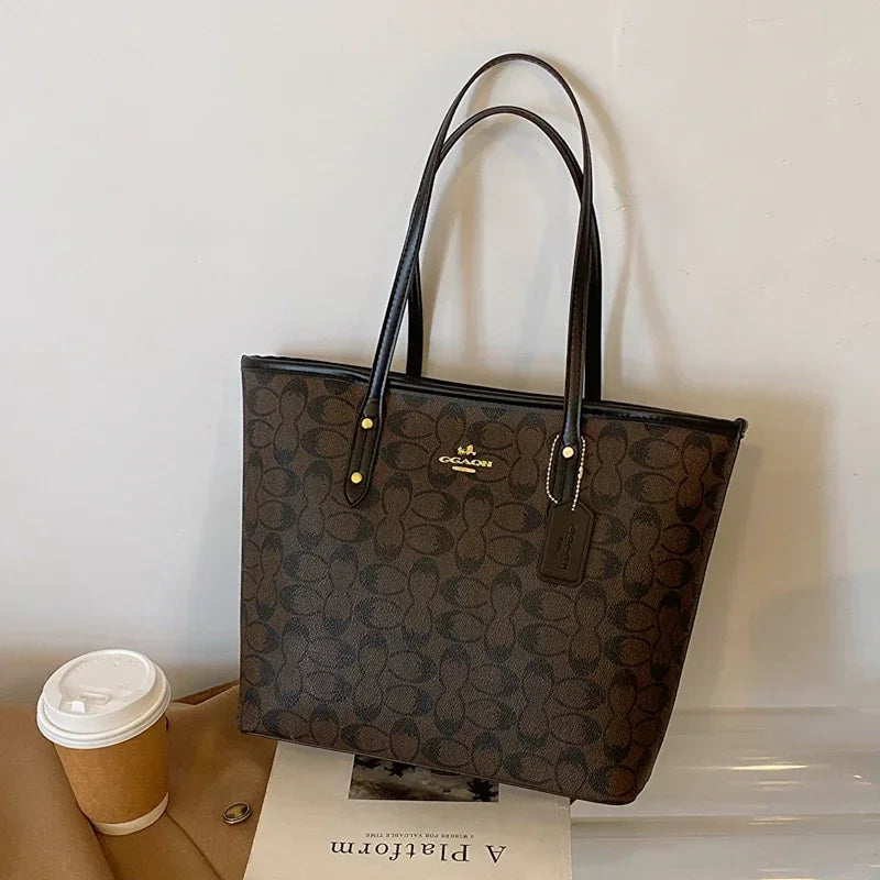 Coach handbag with a coffee cup and paper on a white surface