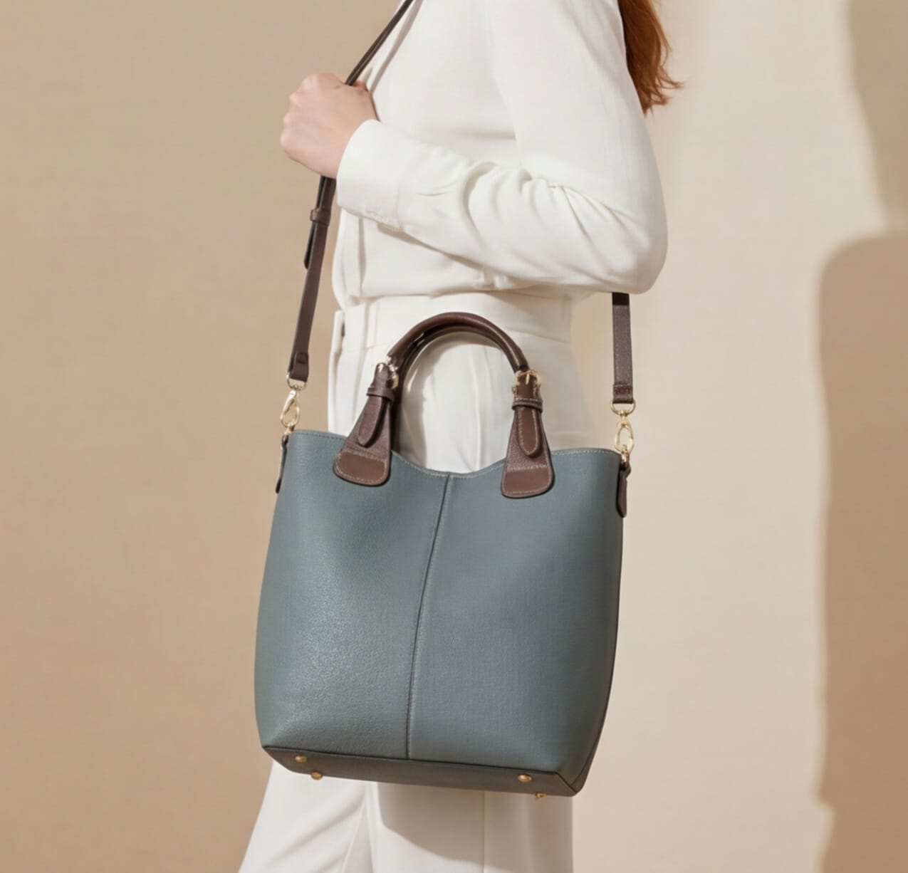 Person holding a green handbag with brown handles against a beige background