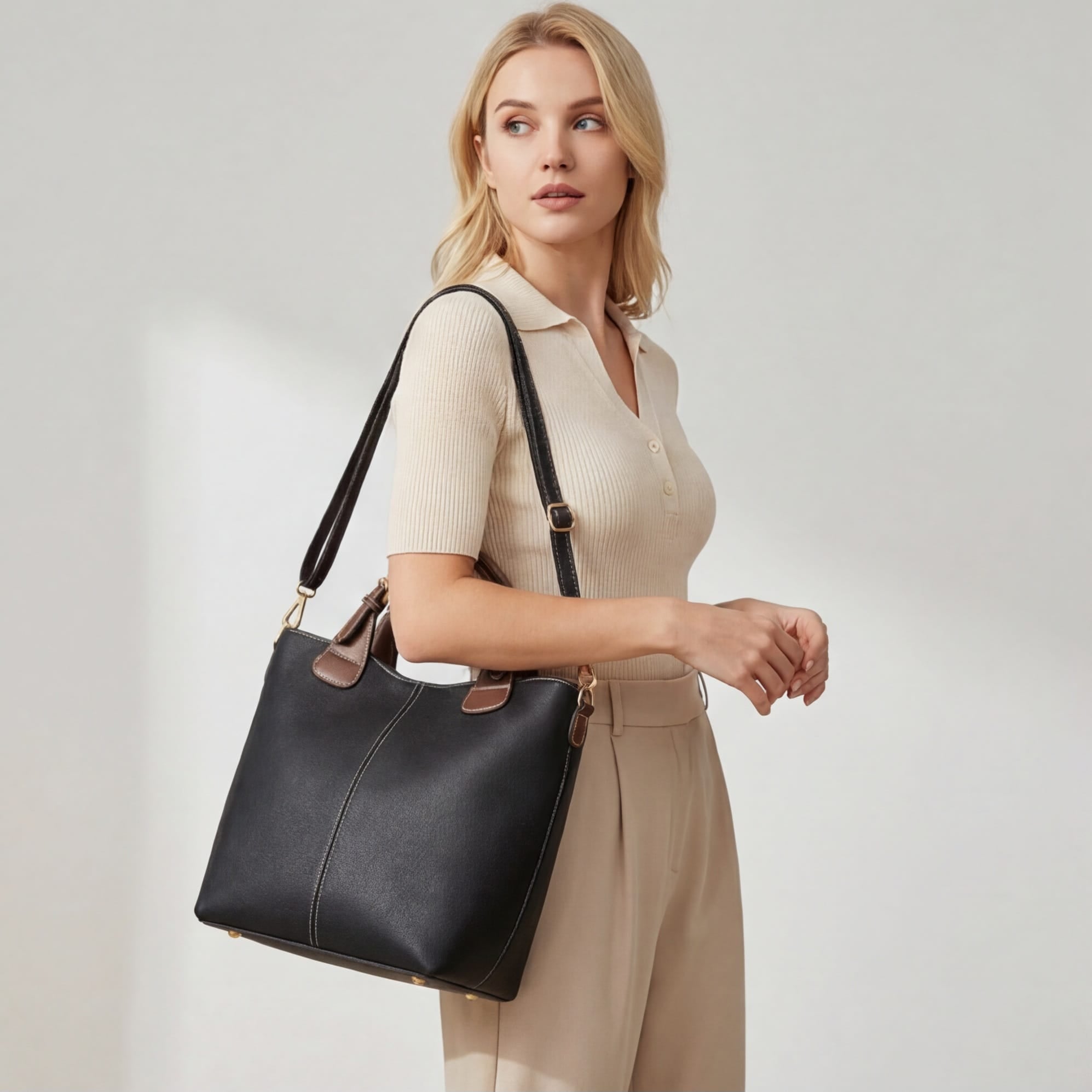 Woman holding a black handbag against a plain background