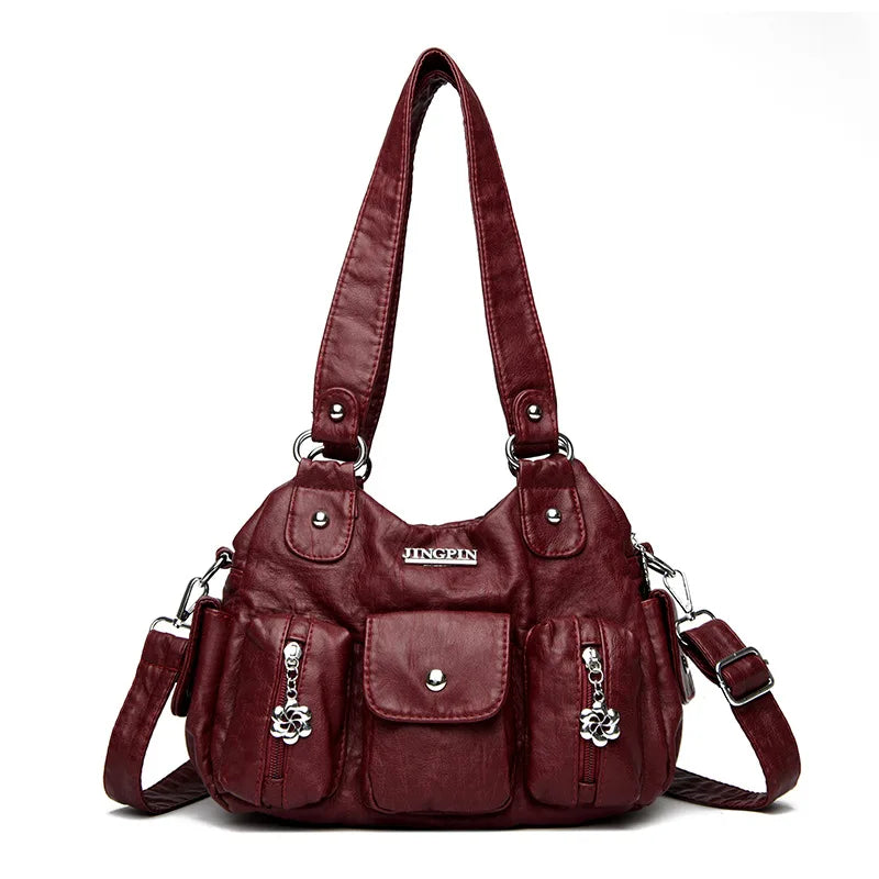 Maroon handbag with multiple pockets and straps on a white background