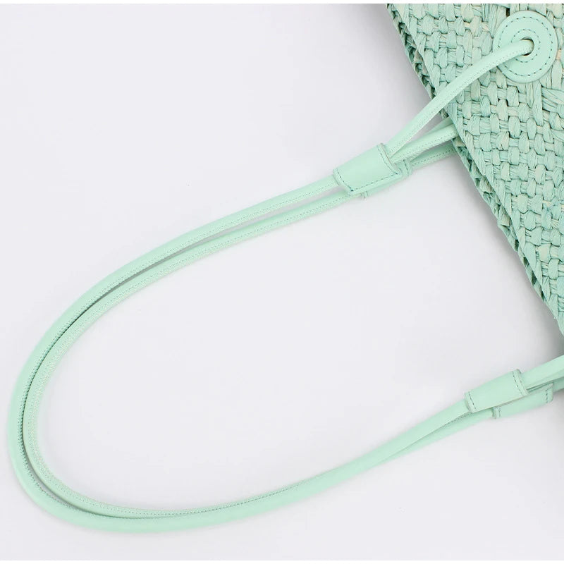Mint green woven bag with matching strap on a light gray background