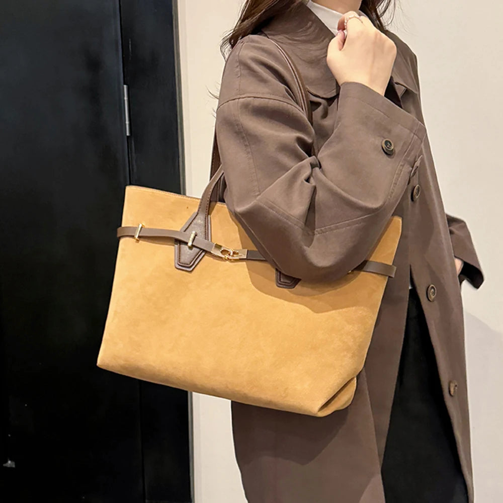 Person holding a beige handbag with a blurred background