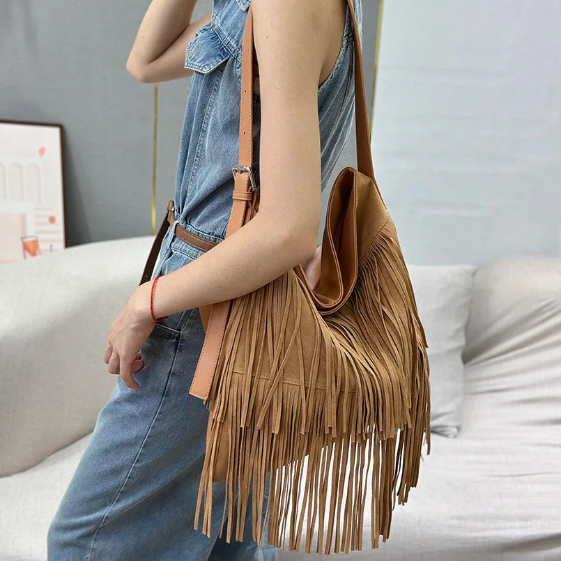 Person holding a brown fringe handbag in a casual setting