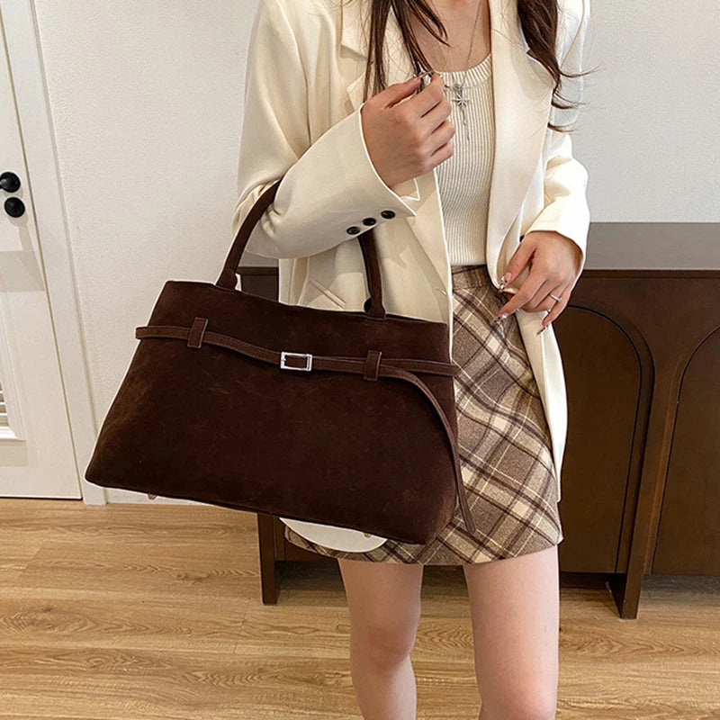 Person holding a brown handbag indoors