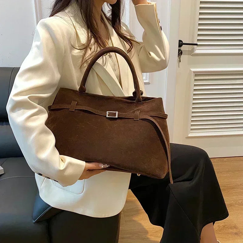 Person holding a brown handbag indoors