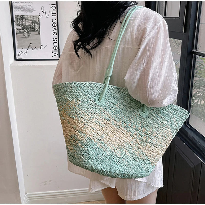Person holding a large woven bag with a gradient of green and beige colors.
