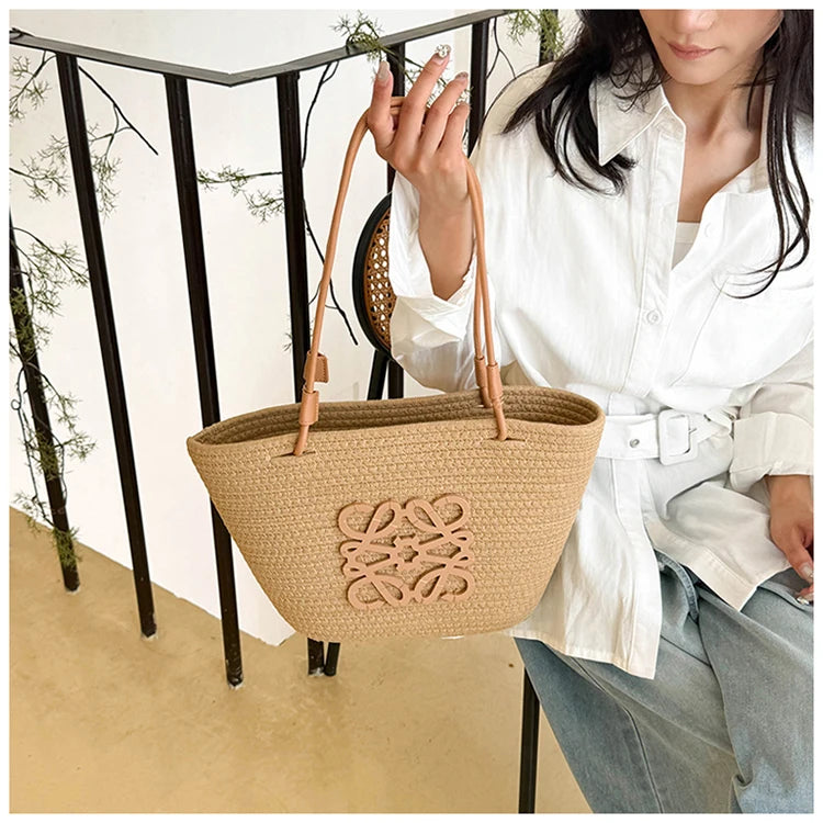 Person holding a woven handbag with a visible brand logo outdoors.