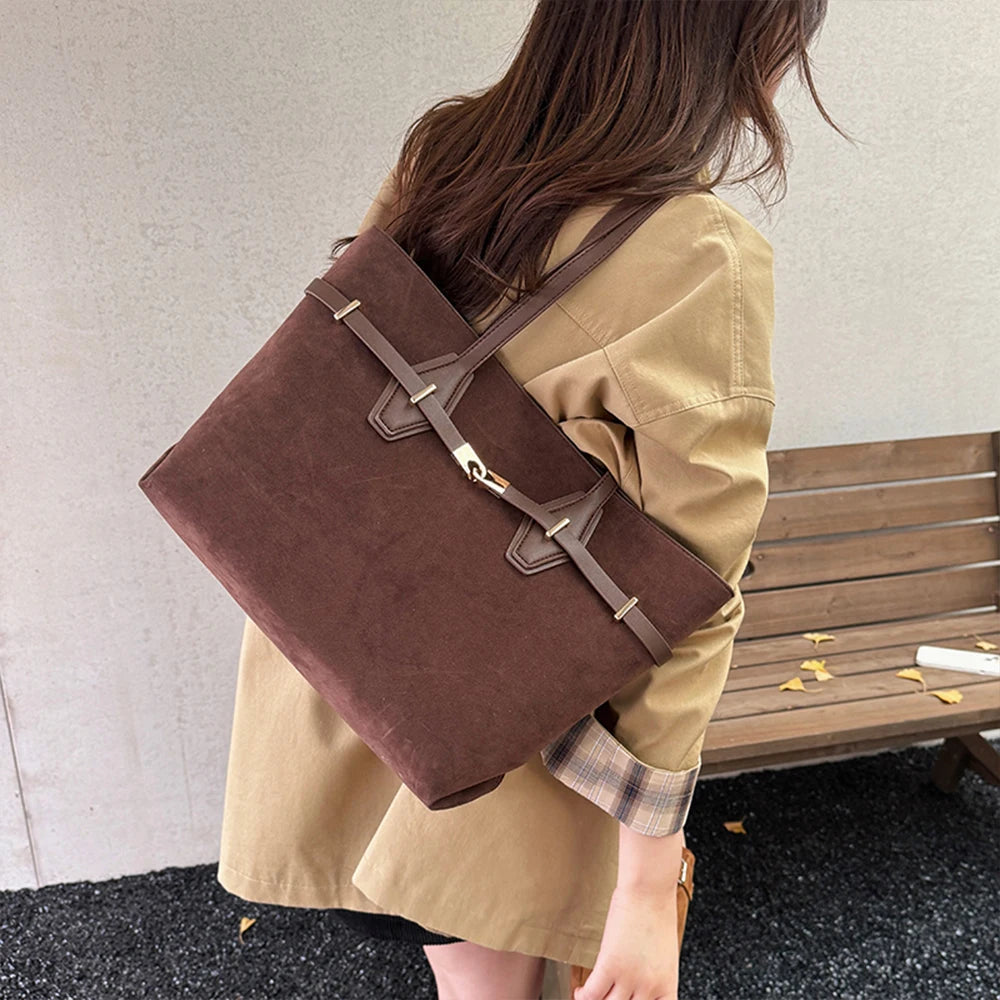 Person wearing a brown leather bag over one shoulder with a neutral background