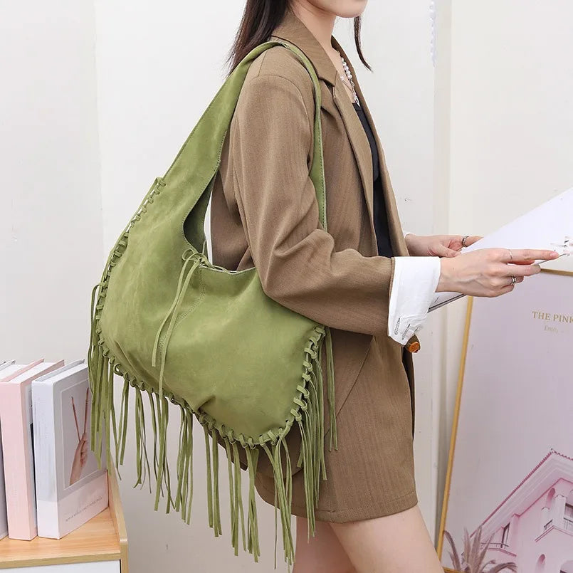 Person wearing a green bag with fringe, standing indoors.