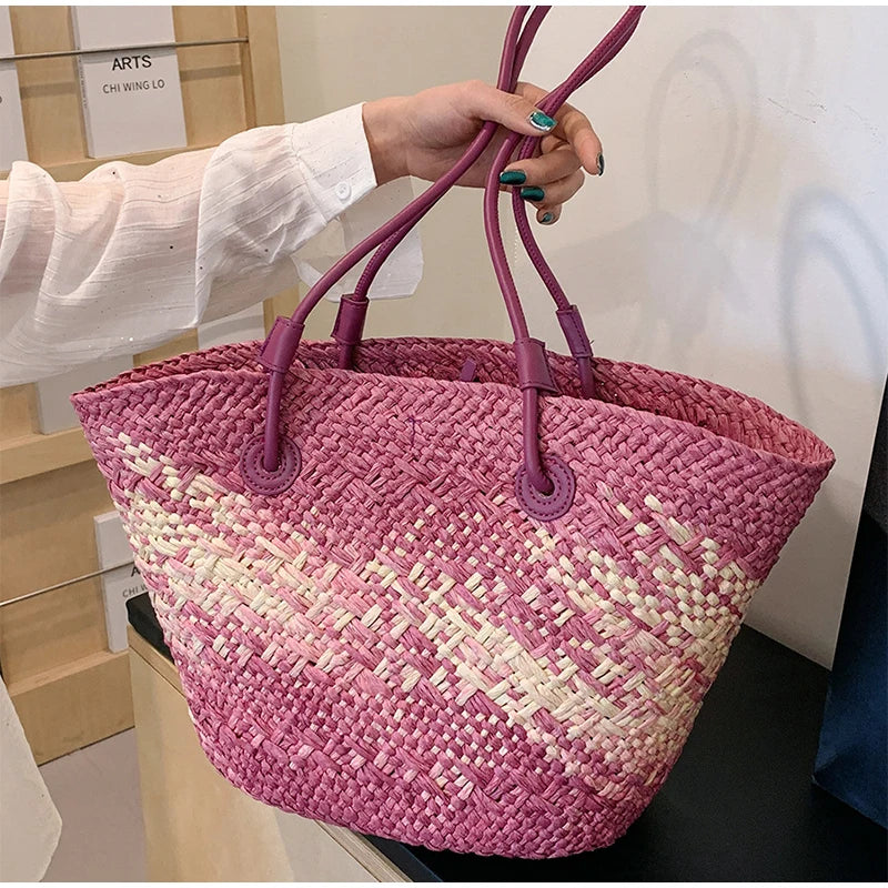 Pink and white woven bag with purple handles held by a person.