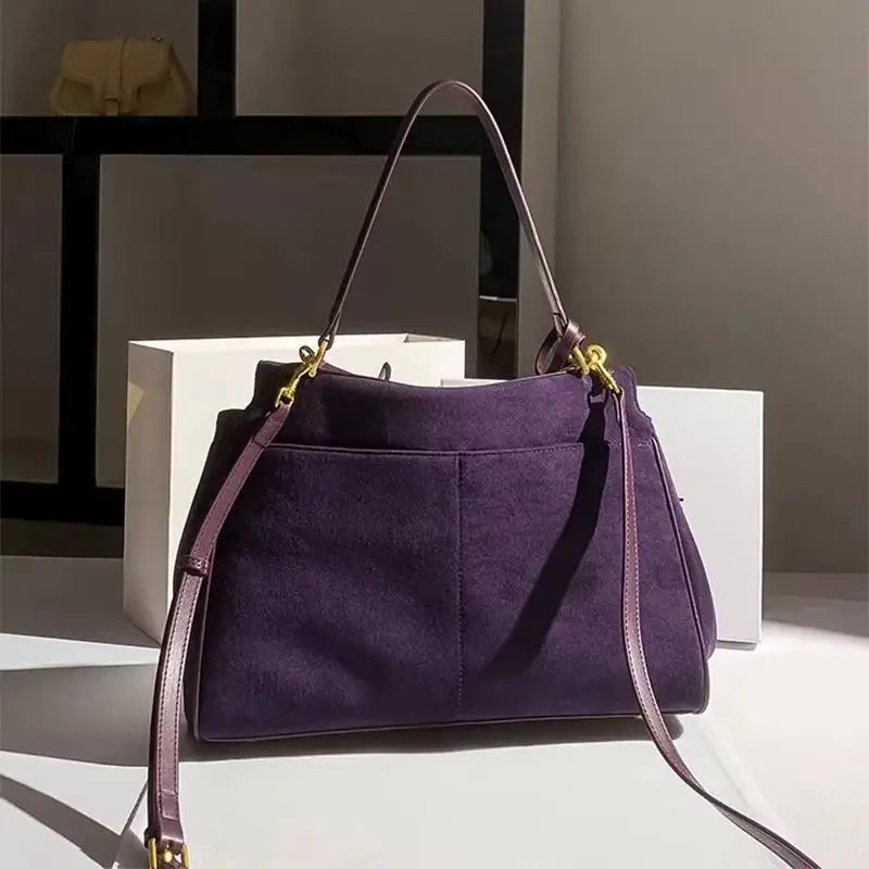 Purple handbag with a strap on a white surface