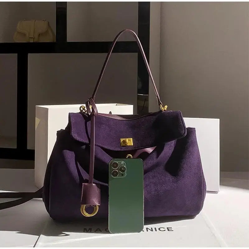 Purple handbag with a visible brand tag on a light surface