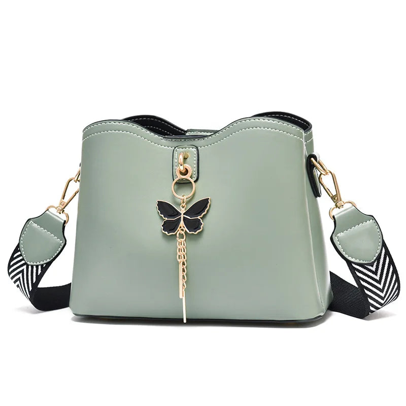 Light green handbag with a butterfly charm on a white background