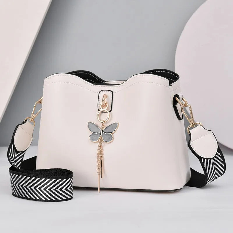 White handbag with a butterfly keychain on a light gray background