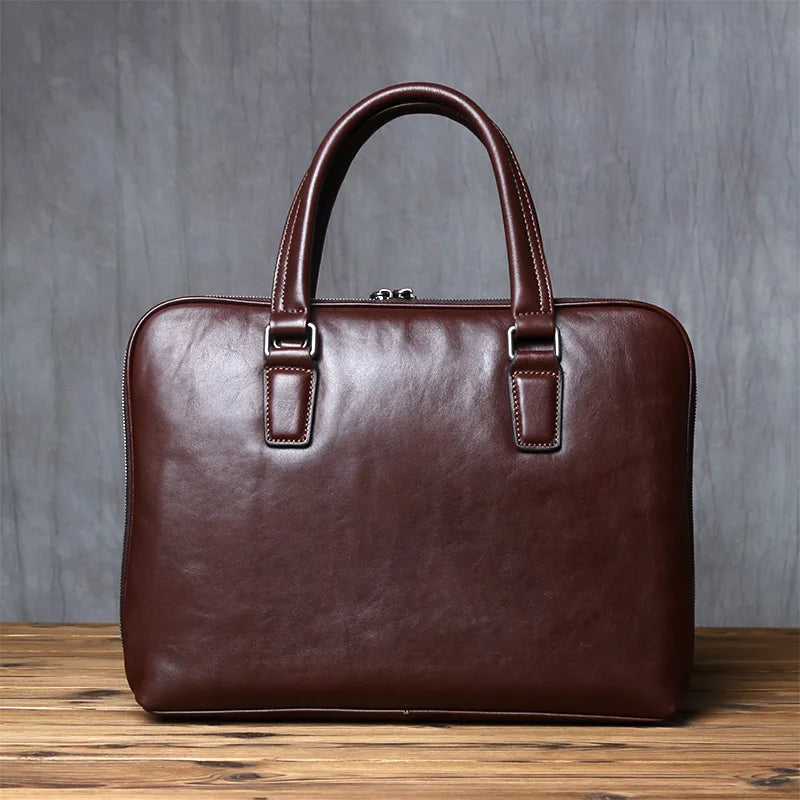 Brown leather briefcase on a wooden surface with a gray concrete wall background