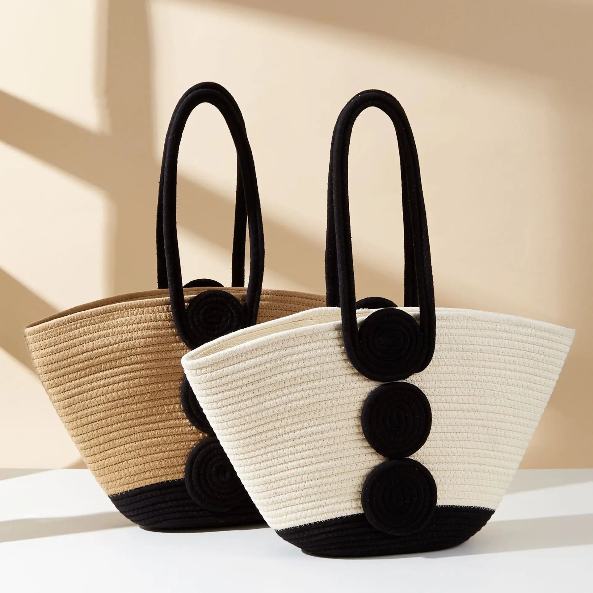 Two woven bags with black handles and pom-pom details on a light background