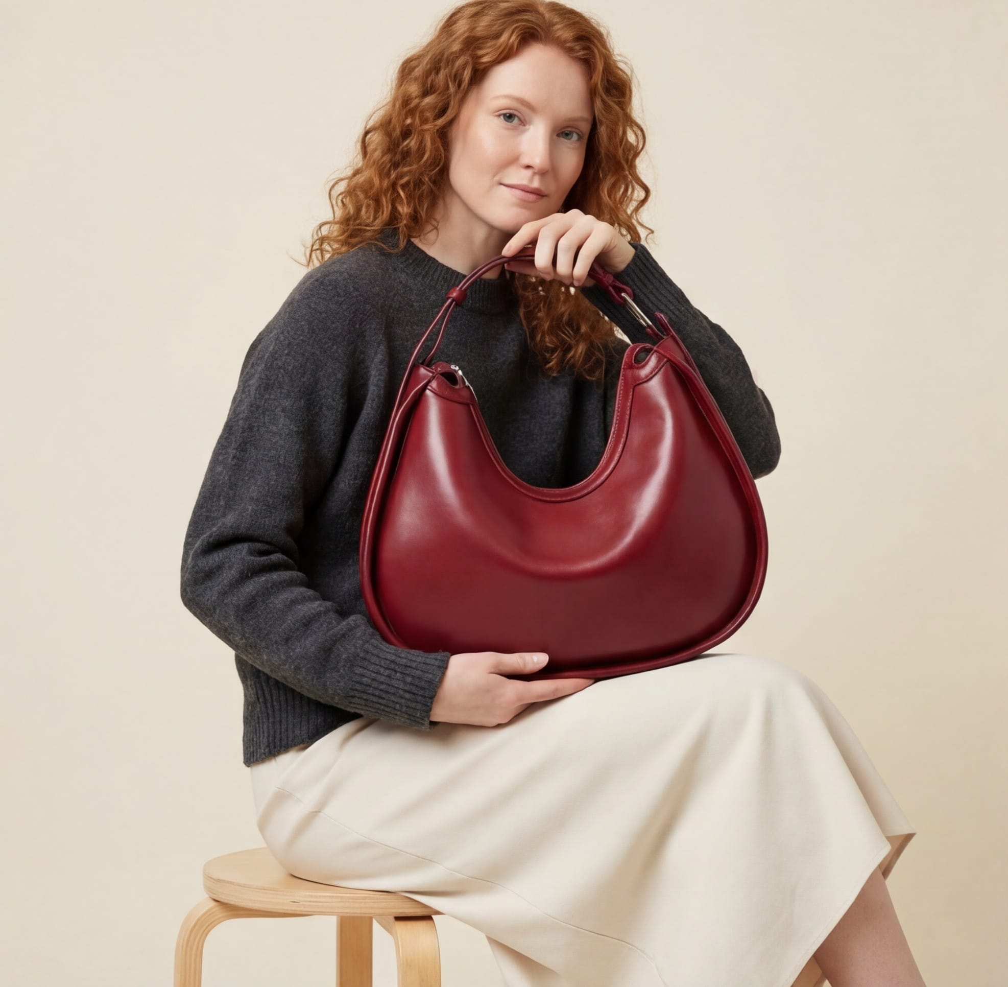 Woman holding a red handbag against a beige background