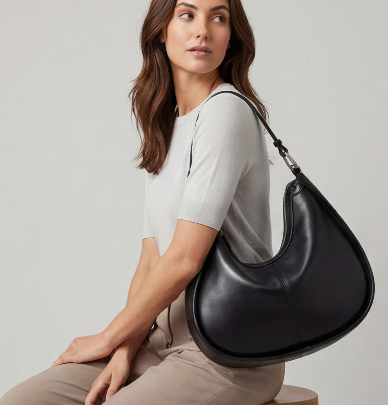 Woman holding a black handbag against a plain background