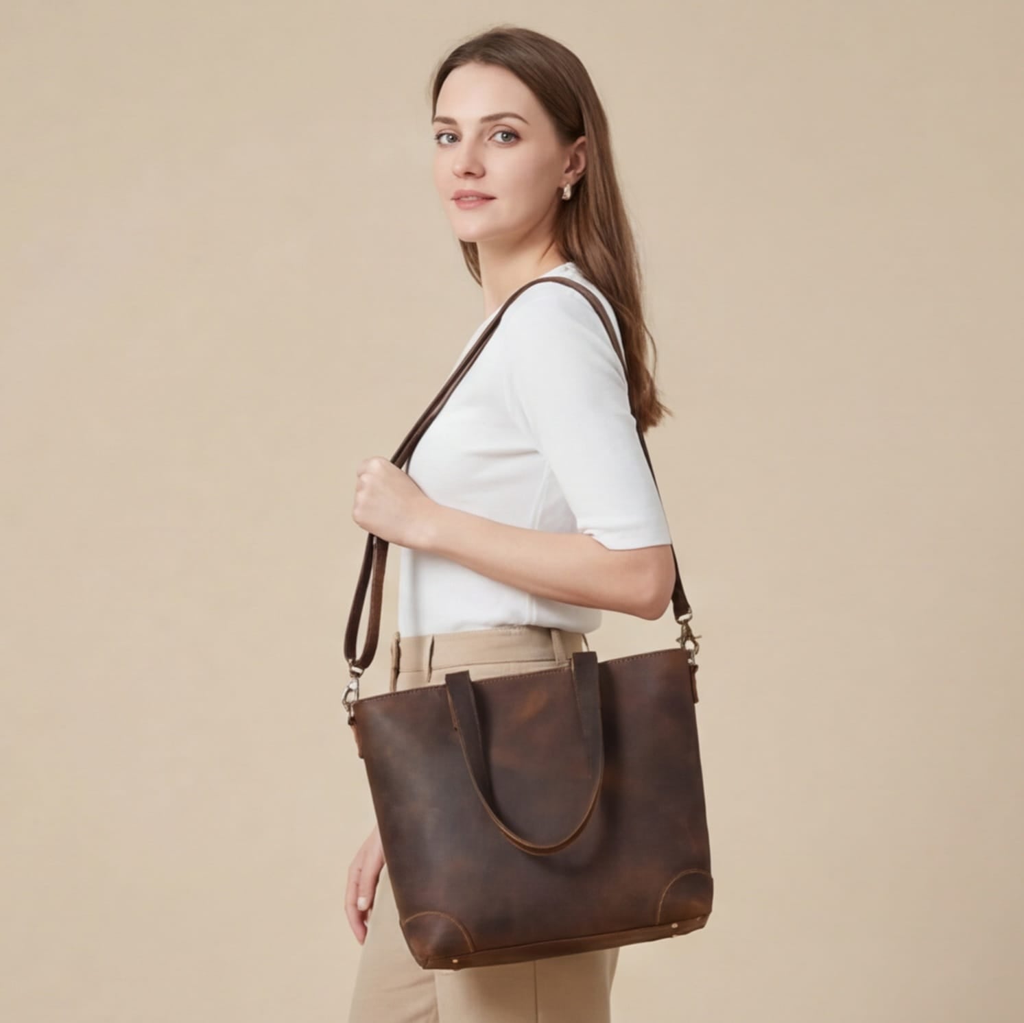 Woman holding a brown leather tote bag against a beige background