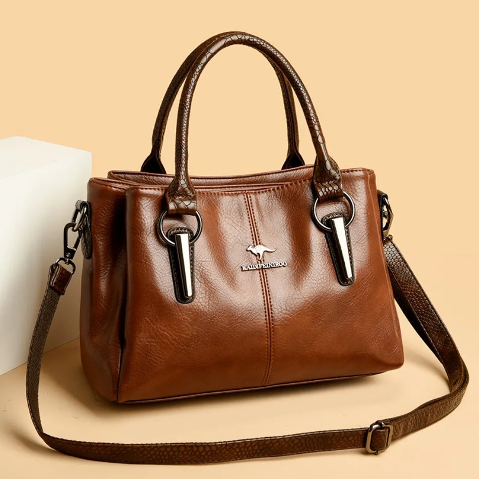 Stylish brown leather handbag with crocodile-patterned handles and an adjustable shoulder strap, displayed against a beige background.