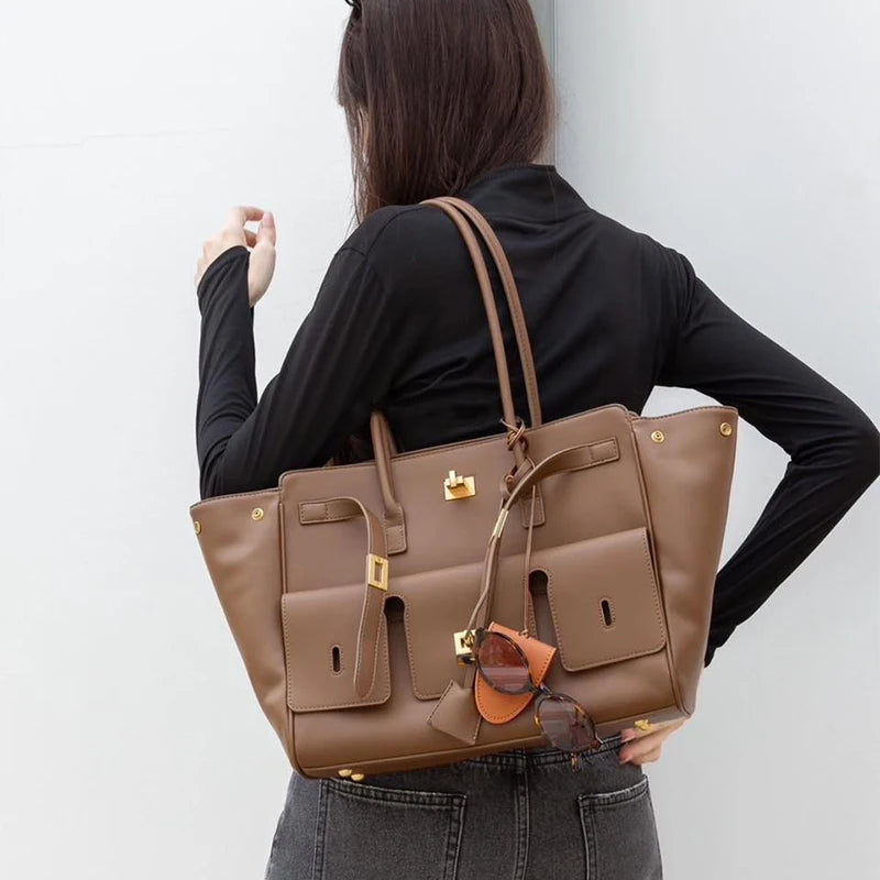 Woman wearing a brown luxury leather tote bag on shoulder – elegant and spacious handbag with gold accents, perfect for work and casual outings