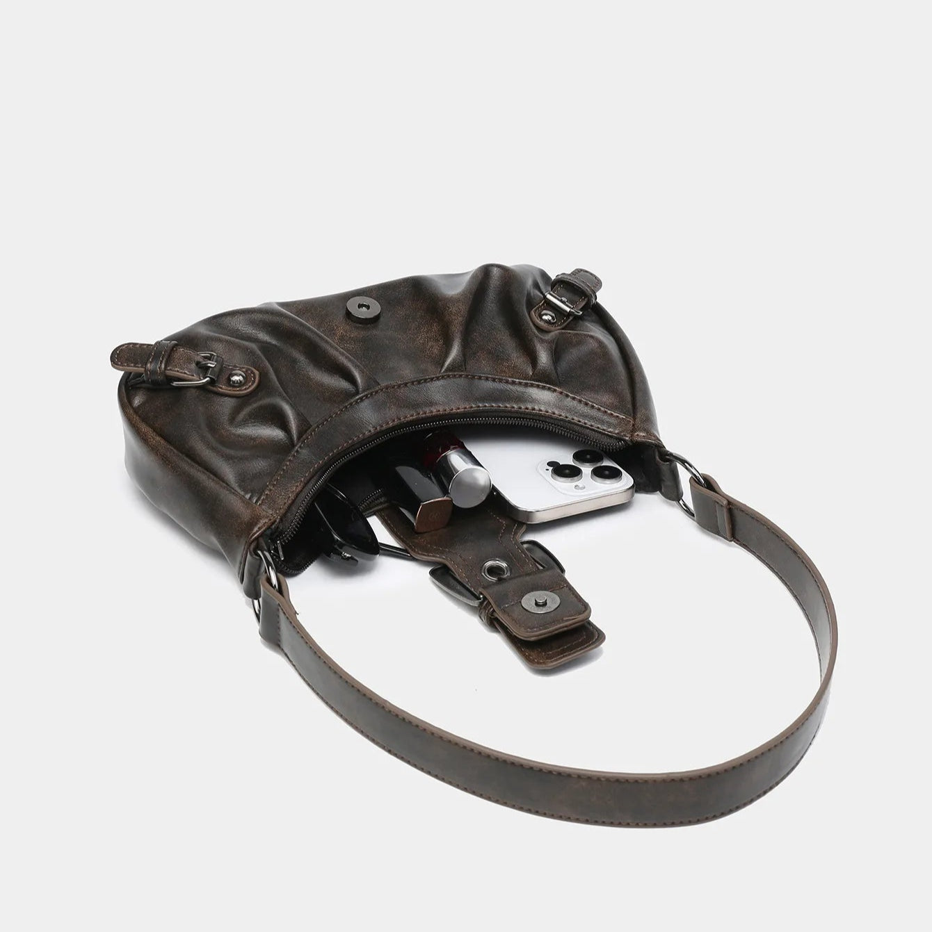 Open dark brown leather shoulder bag showing contents including phone, lipstick, and other small items.