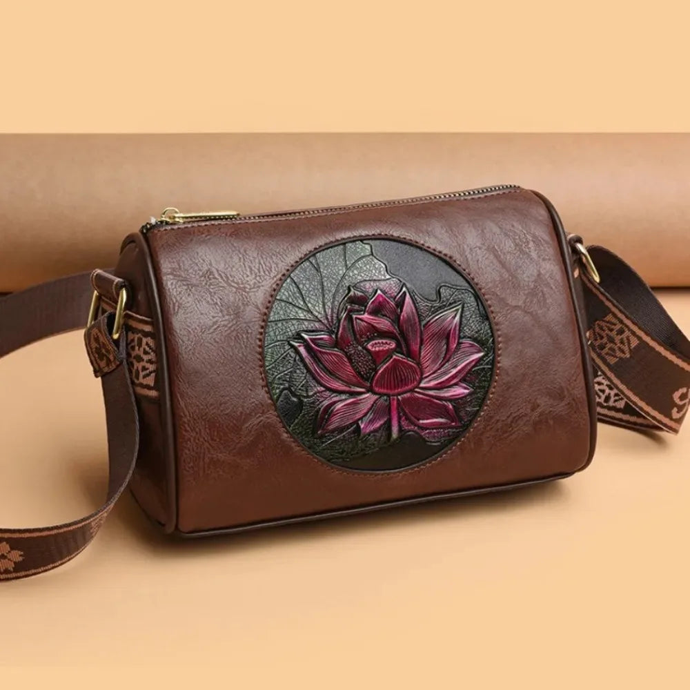 Vintage floral leather crossbody bag in brown with an embossed red lotus design, displayed on a neutral beige background.